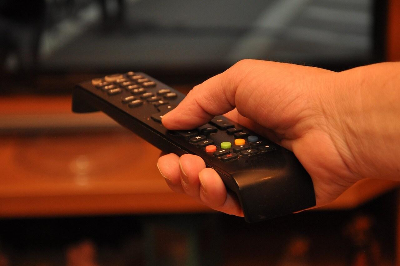 A Hand Holds a Remote Control