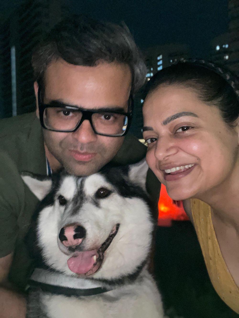 a man and woman taking a selfie with a dog