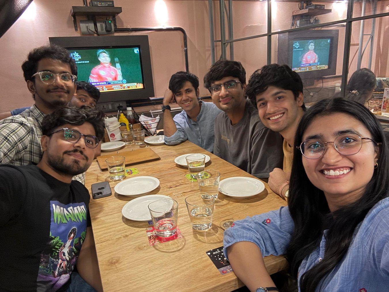 a group of people sitting at a table in front of a television