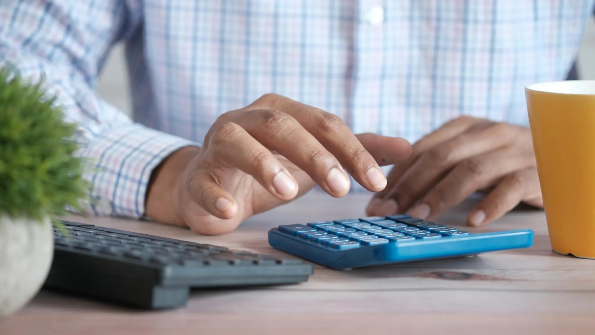 man using a calculator to compute taxes when transferring llc to another state