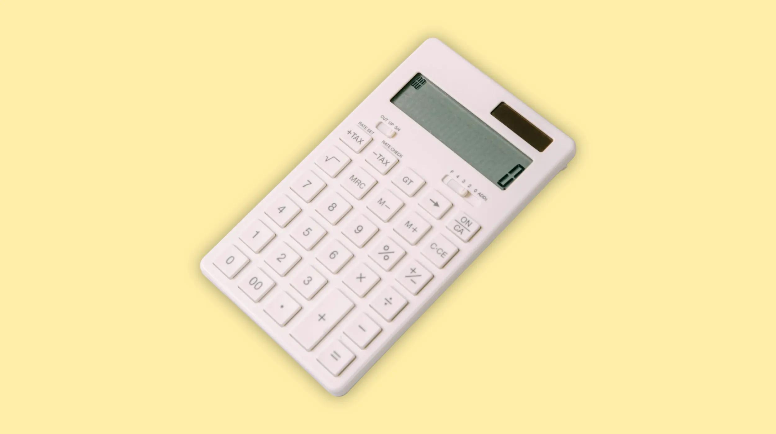a white calculator on a light yellow surface