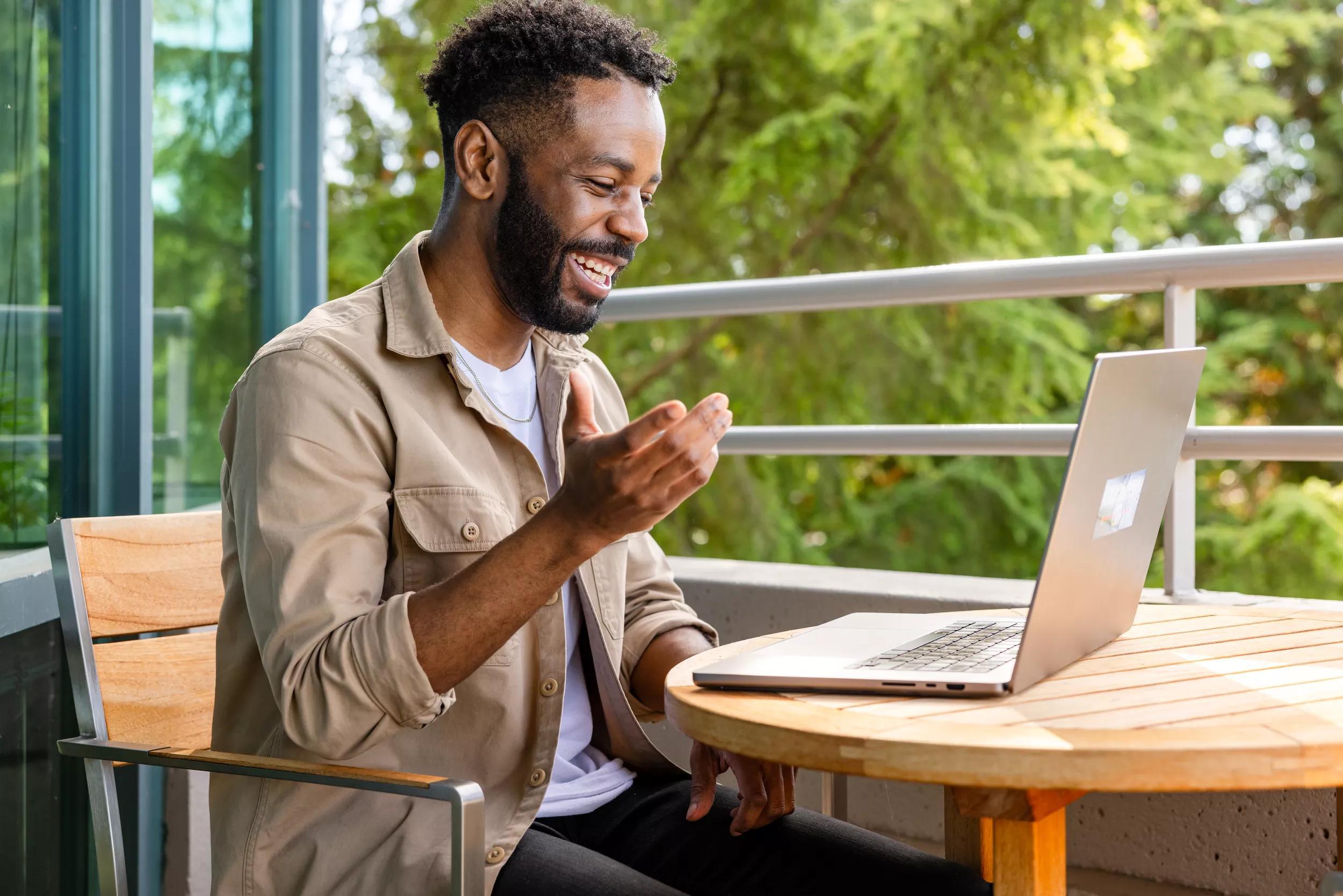 Man smiling and sitting outside while taking video call