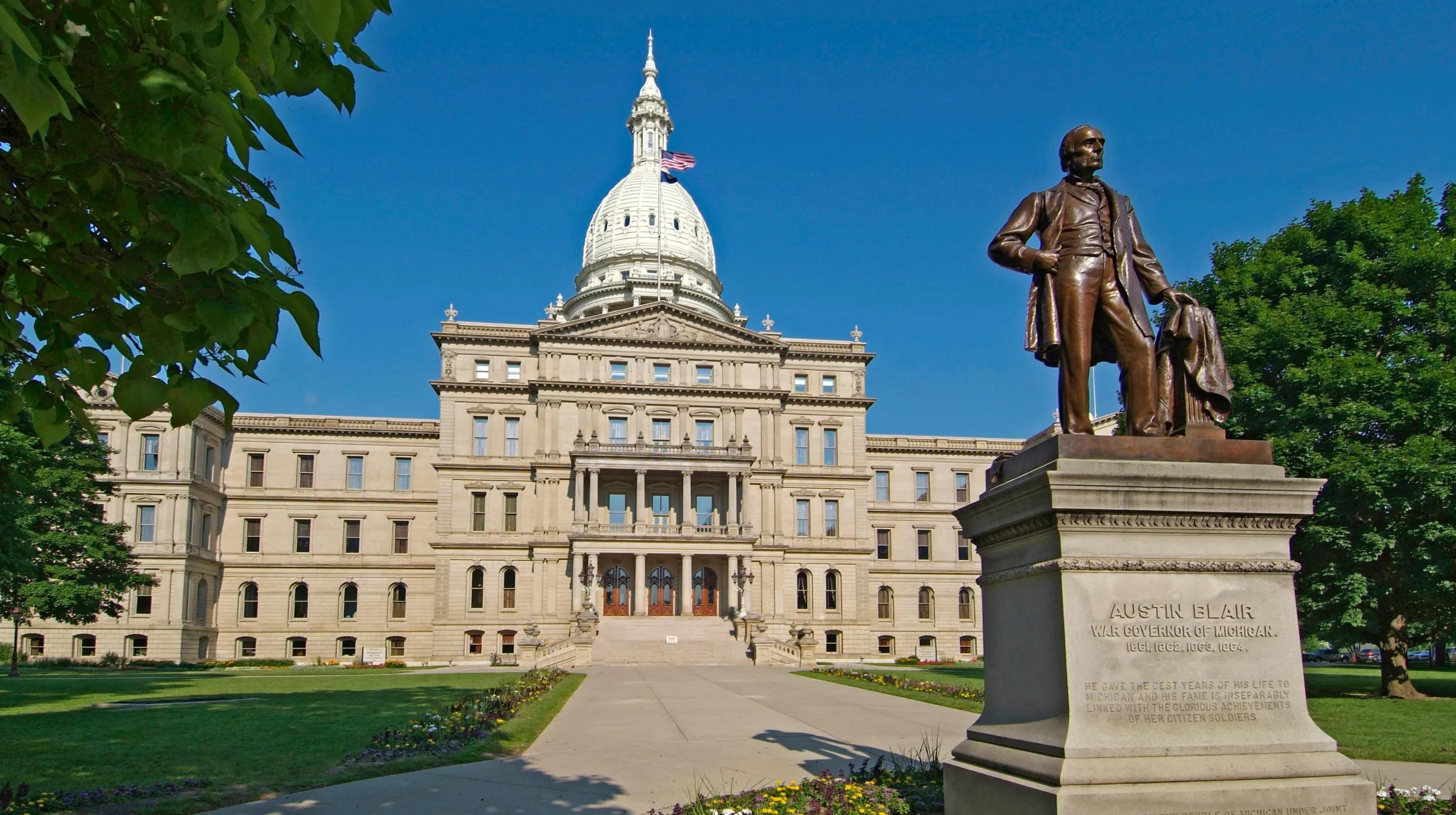 a statue of a person on a horse in front of Michigan State Capitol