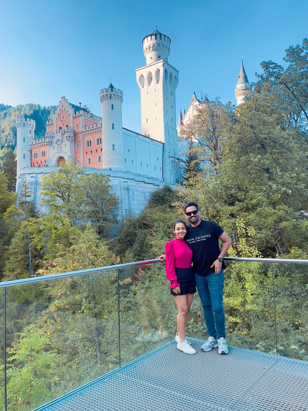 a man and woman posing for a picture in front of a castle