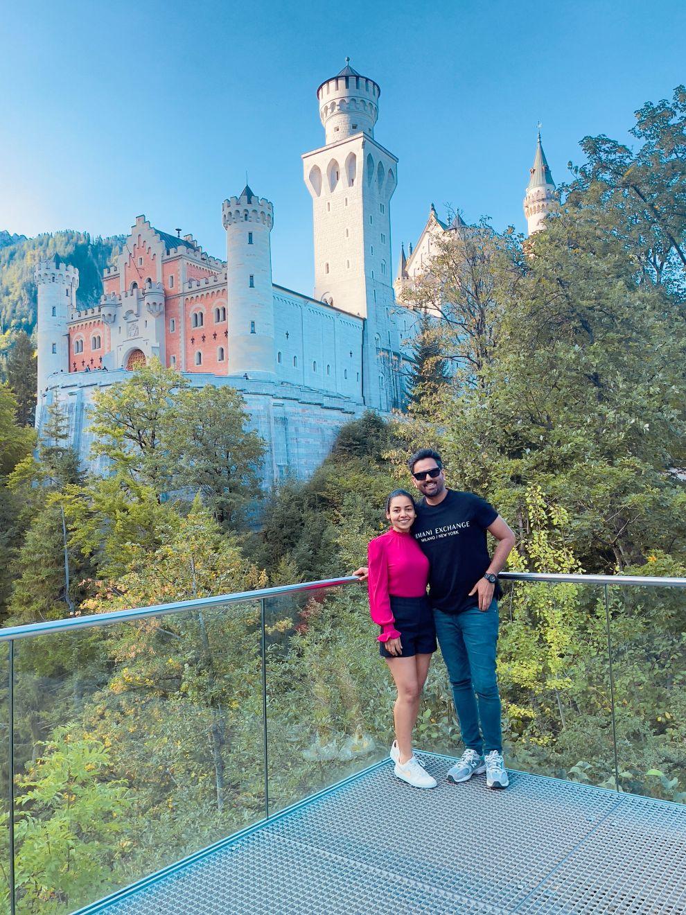 a man and woman posing for a picture in front of a castle