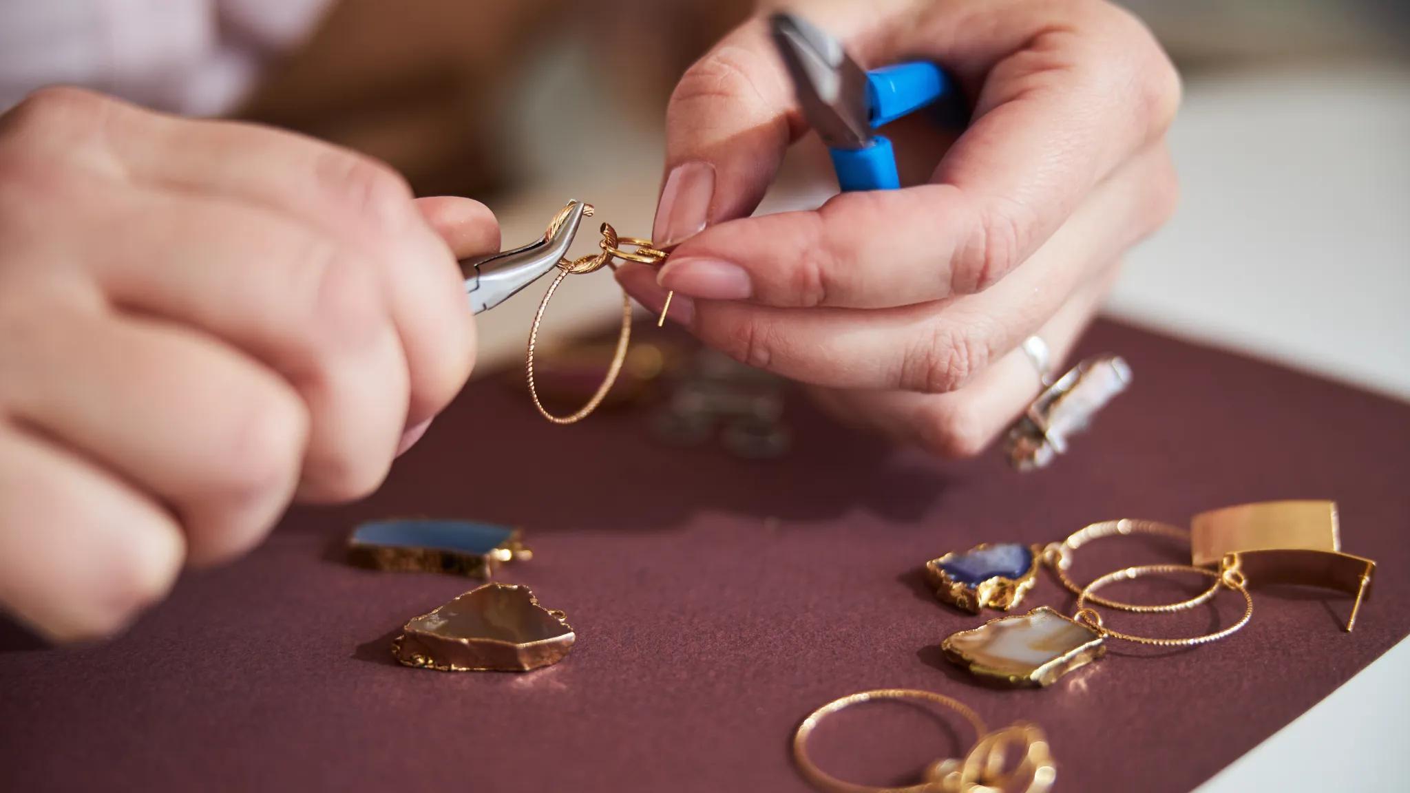 A jeweler bending wire to make a pair of gold earrings.