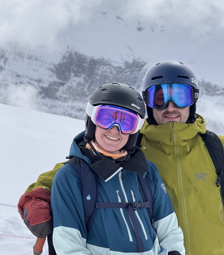 a couple of people wearing helmets and goggles on a snowy mountain