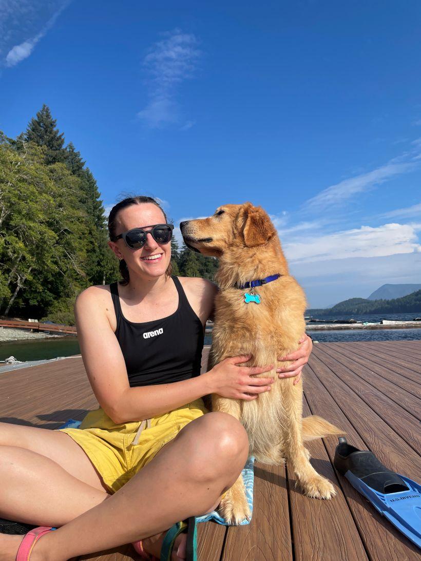 a woman sitting on a dock with a dog