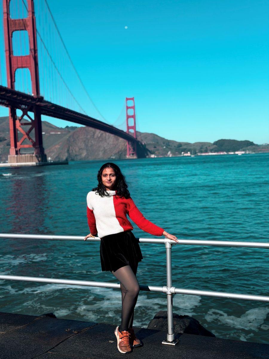 a person posing in front of a large red bridge