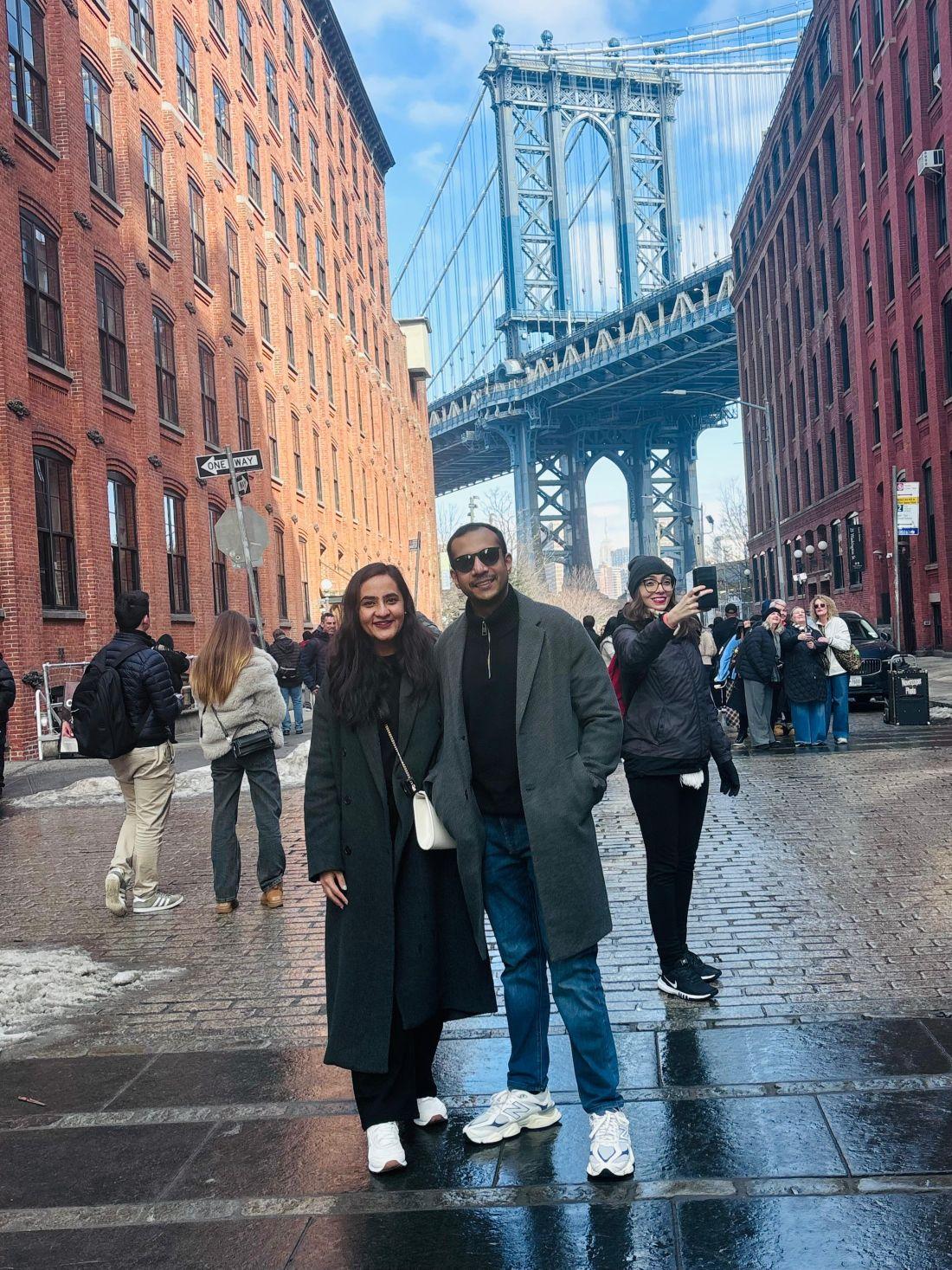 a man and woman posing for a picture under a bridge