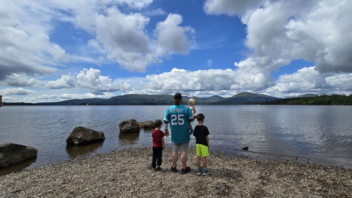 a group of people standing on a rocky shore by a body of water