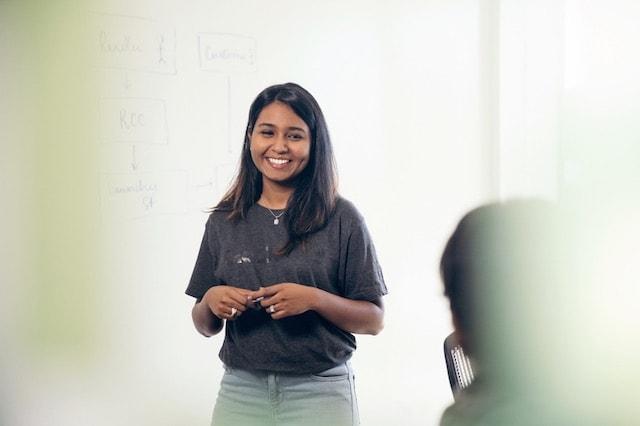 Female GoDaddy Employee Smiling at Whiteboard