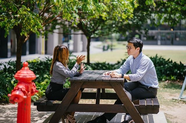 Two People Having A Discussion At A Picnic Bench