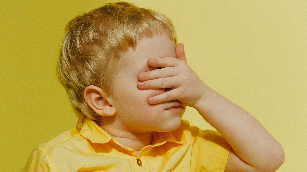 Small Boy Covering His Eyes Illustrating Reaction To Negative Social Media Comments