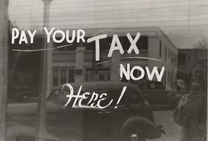 Pay Your Tax Now Here Written on Storefront Window