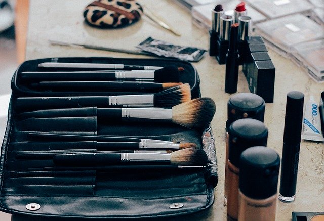 Makeup Brushes And Makeup Scattered On Desk