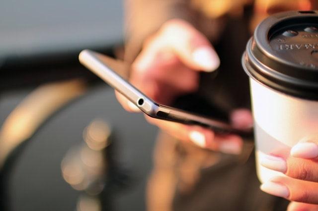 Woman Holding Smartphone And Coffee