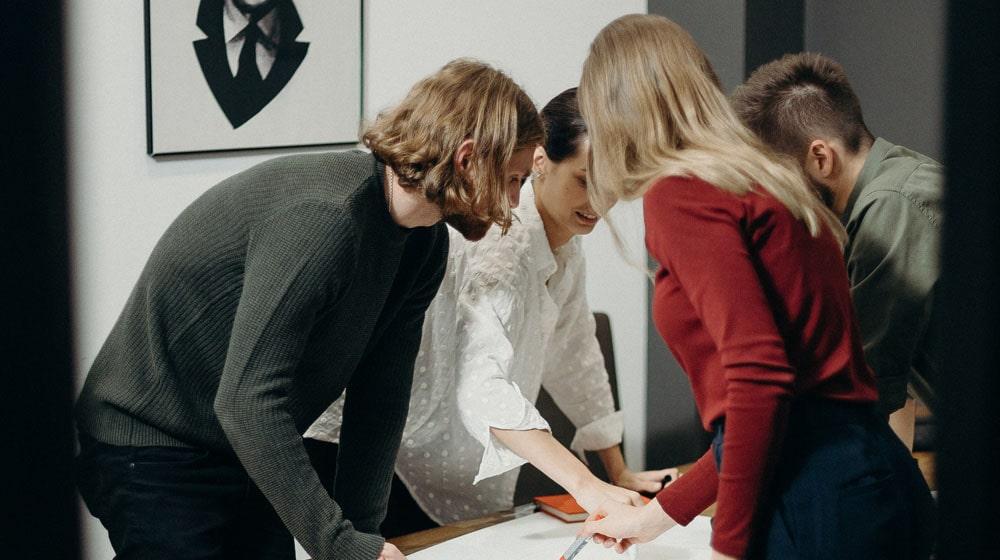 Three Women One Man Around Table Illustrates Mentorship for Women in Tech
