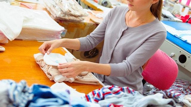 Woman Folding Clothing to Ship Represents Retail Inventory Management